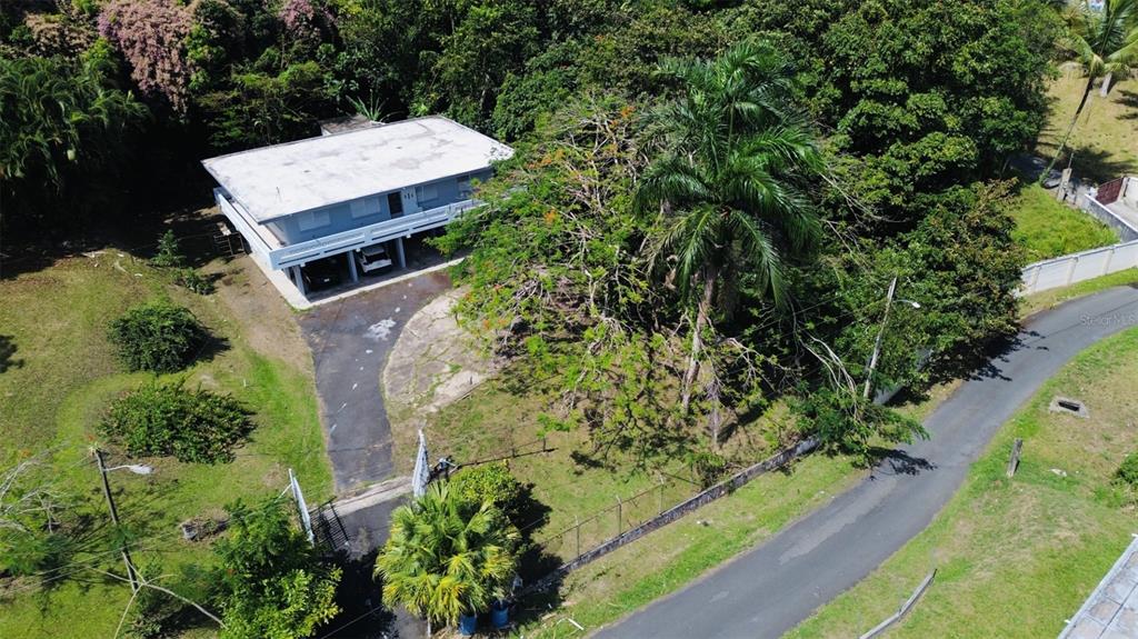 An aerial view shows a two-story house with a carport, surrounded by trees and vegetation — Bo Ciénega Alta SECTOR LA RUEDA CARR#959 UNIT Solar -A, RIO GRANDE, PR