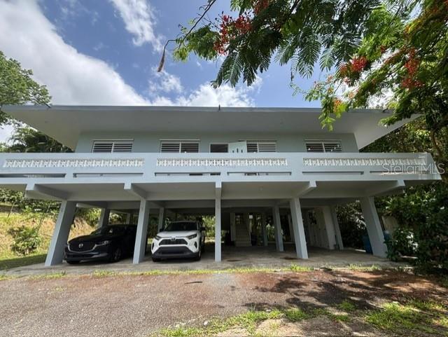 A light blue house on stilts features a balcony and a covered ground-level parking area — Bo Ciénega Alta SECTOR LA RUEDA CARR#959 UNIT Solar -A, RIO GRANDE, PR