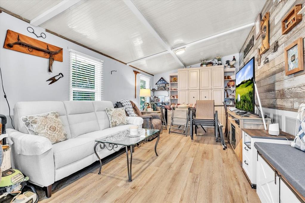 A living room features a white sofa, a glass coffee table, and wood-look flooring — 10933 BROWN PELICAN CIRCLE, ESTERO, FL