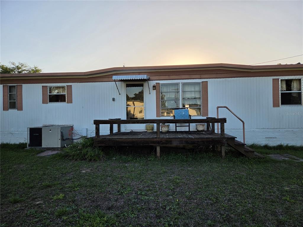 A single-story mobile home with white siding, brown trim, and a wooden front deck — 17420 SE 36TH LANE, OCKLAWAHA, FL