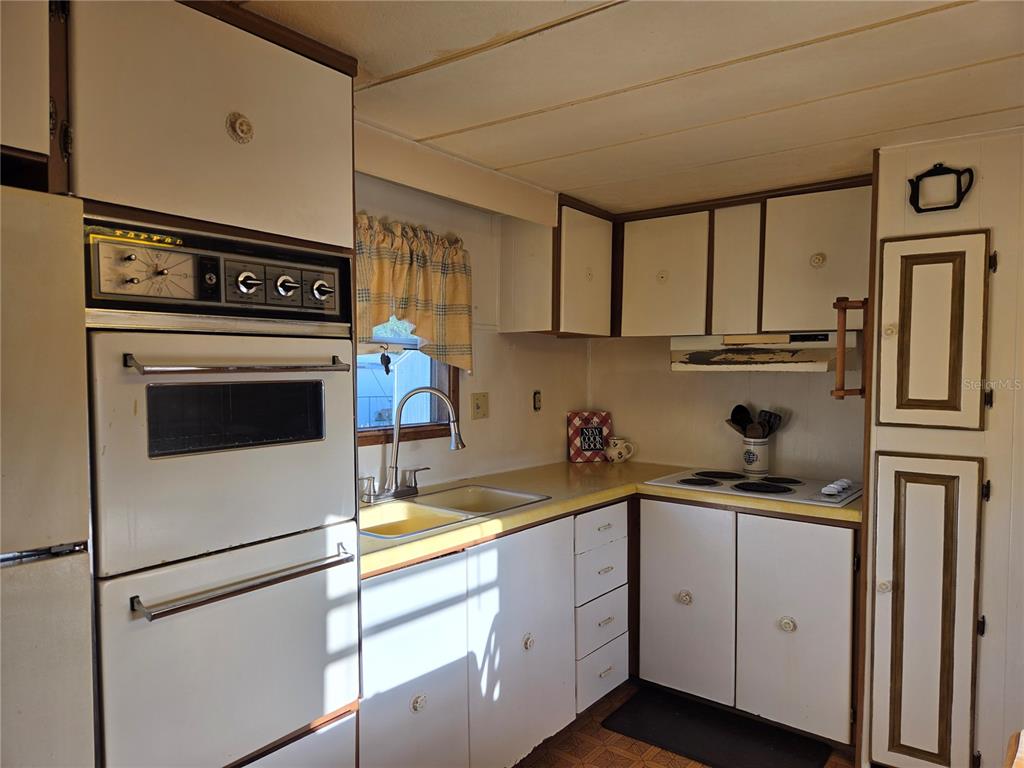 A kitchen features white cabinets, a wall oven, a sink, and a cooktop — 17420 SE 36TH LANE, OCKLAWAHA, FL
