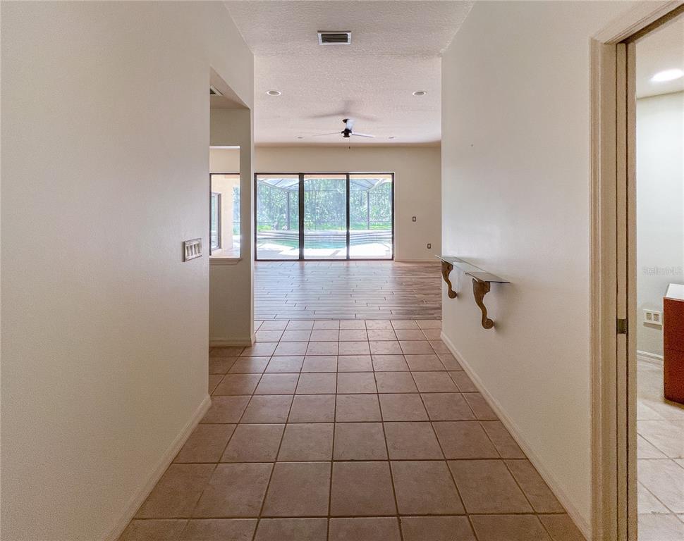 A tiled entryway leads to a living area with sliding glass doors overlooking a pool — 9020 SHENANDOAH RUN, WESLEY CHAPEL, FL
