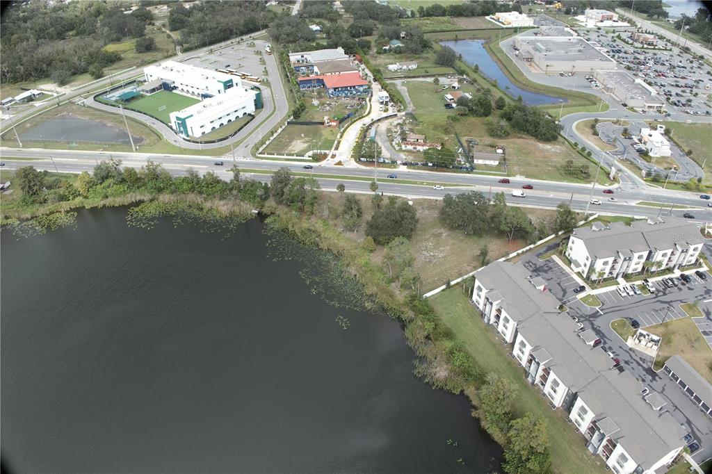 An aerial view shows a lake, a multi-lane road, and several commercial and residential buildings — 233 RONALD REAGAN PARKWAY, DAVENPORT, FL