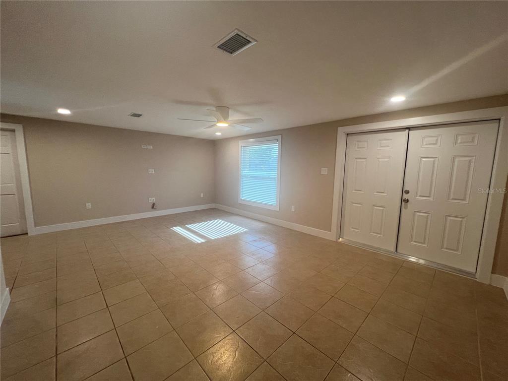 An empty room with beige tile flooring, light-colored walls, a ceiling fan, and double doors — 249 SEMINOLE BOULEVARD NW, PORT CHARLOTTE, FL