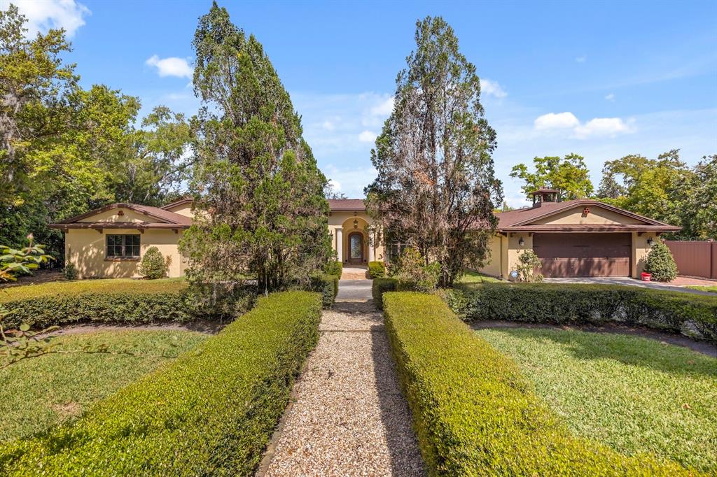 A single-story house with a gravel path, manicured hedges, and a two-car garage — 5400 KENMORE LANE, ORLANDO, FL