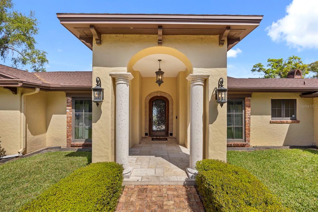 The exterior of a house features a covered entryway with two columns and a decorative door — 5400 KENMORE LANE, ORLANDO, FL