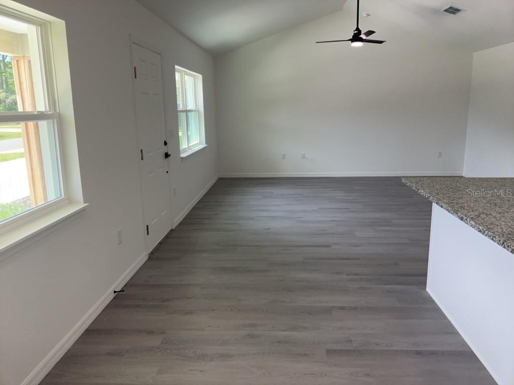 A bright living area features gray wood-look flooring, white walls, and a vaulted ceiling — 14173 SW 60TH TERRACE UNIT 2, OCALA, FL