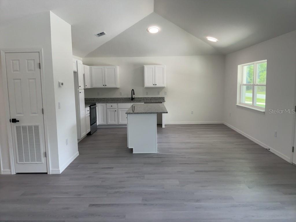 A kitchen and dining area with white cabinets, granite countertops, and light gray wood flooring — 14173 SW 60TH TERRACE UNIT 2, OCALA, FL