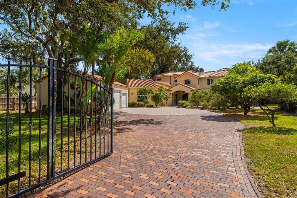 A paved driveway leads to a two-story house with a tile roof and gated entrance — 7240 DR MARTIN LUTHER KING JR STREET S, ST PETERSBURG, FL