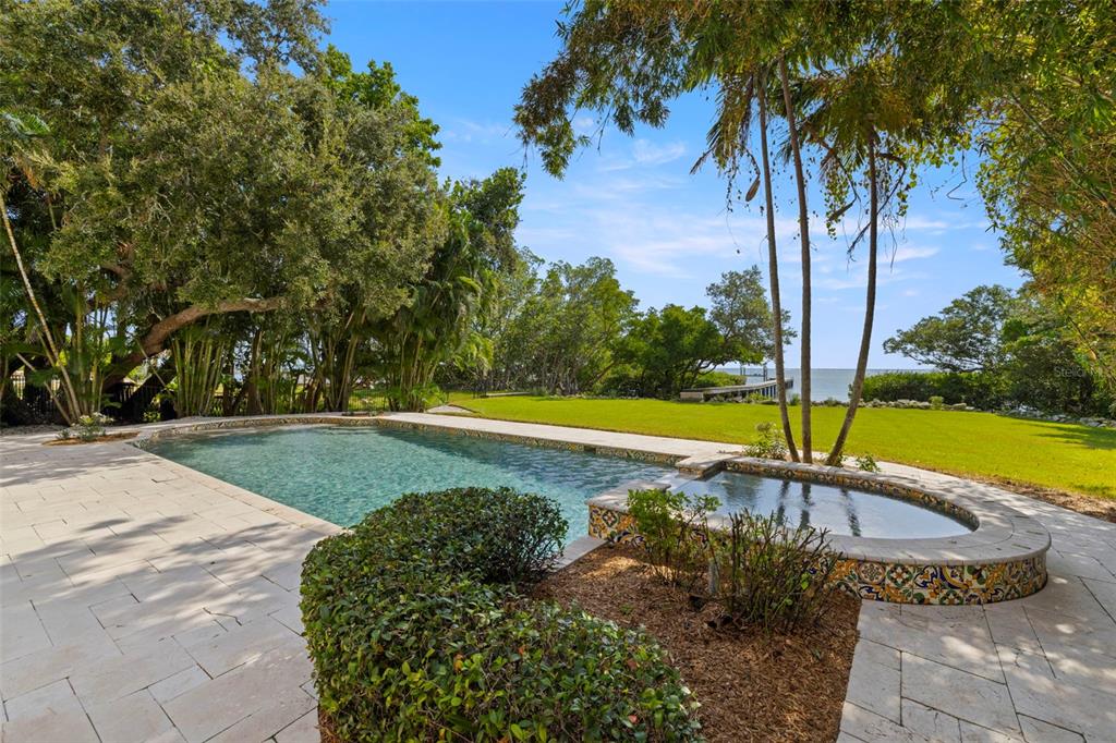 A backyard swimming pool and hot tub overlook a grassy lawn and a distant bay — 7240 DR MARTIN LUTHER KING JR STREET S, ST PETERSBURG, FL