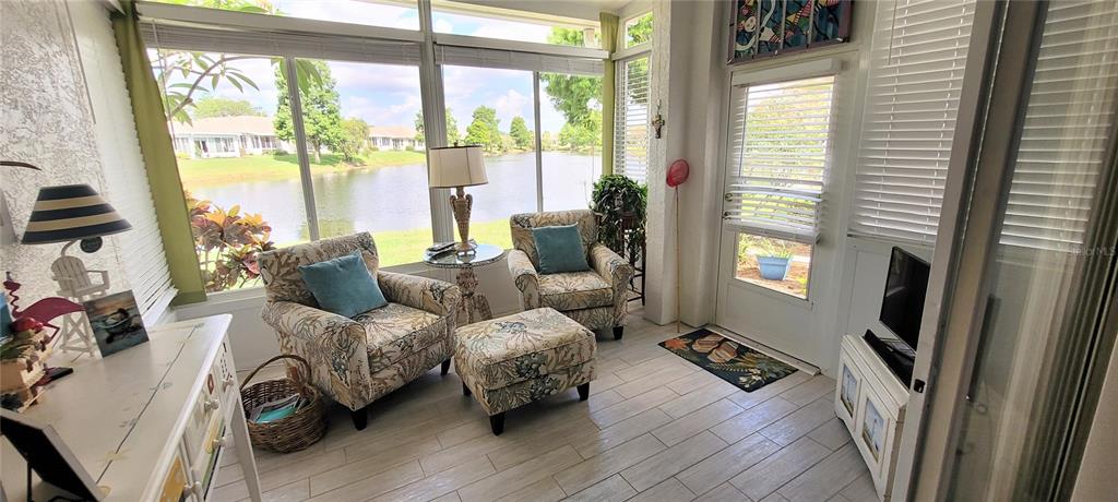 A sunroom with tile floors, two patterned armchairs, and a view of a lake — 834 TREMONT GREENS LANE UNIT 137, SUN CITY CENTER, FL