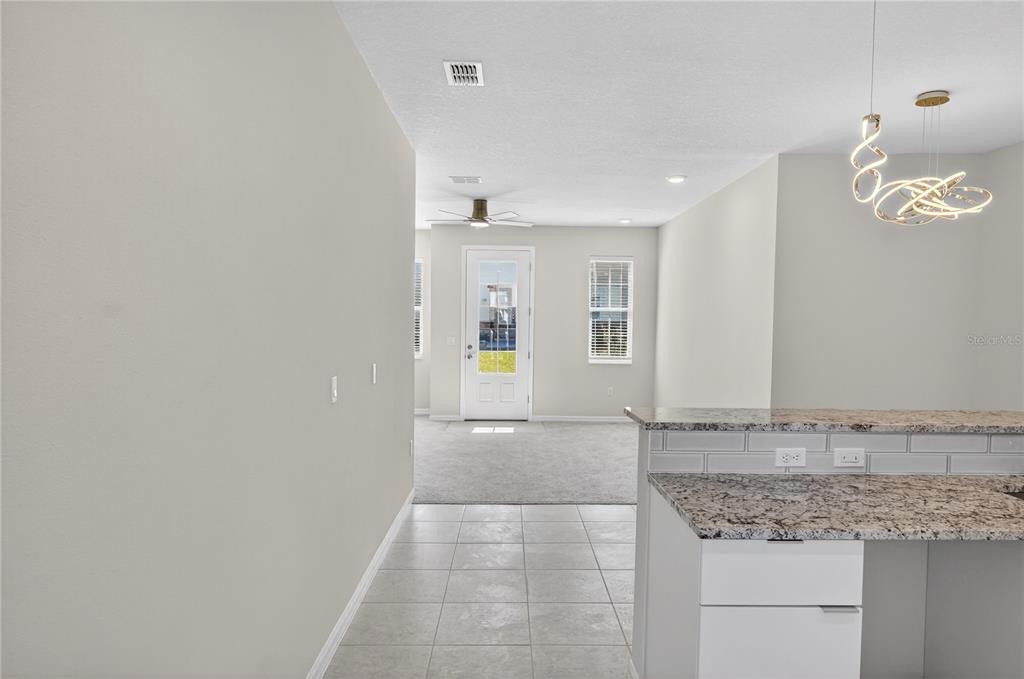 A view from a kitchen with granite countertops looking toward a carpeted living area — 176 HOLLY VILLAGE DRIVE, DAVENPORT, FL