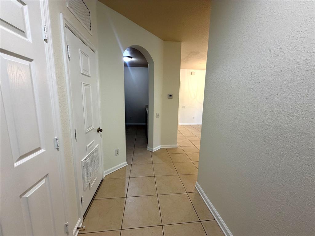 A tiled hallway leads to an arched doorway and an open living area beyond — 6084 STEVENSON DRIVE UNIT 204, ORLANDO, FL