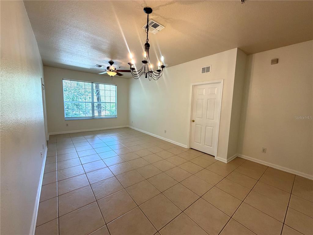 A dining room features tan tile flooring, a chandelier, a ceiling fan, and a window — 6084 STEVENSON DRIVE UNIT 204, ORLANDO, FL