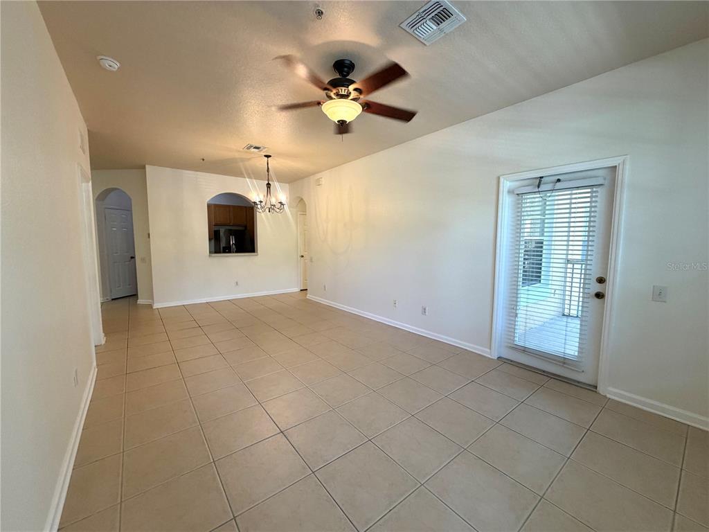 An open-concept living and dining area features tile flooring, a ceiling fan, and glass doors — 6084 STEVENSON DRIVE UNIT 204, ORLANDO, FL