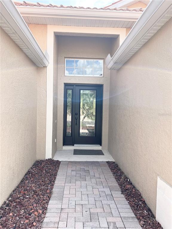 A paved walkway leads to a front door with a sidelight and a transom window — 2344 CARAWAY DRIVE, VENICE, FL