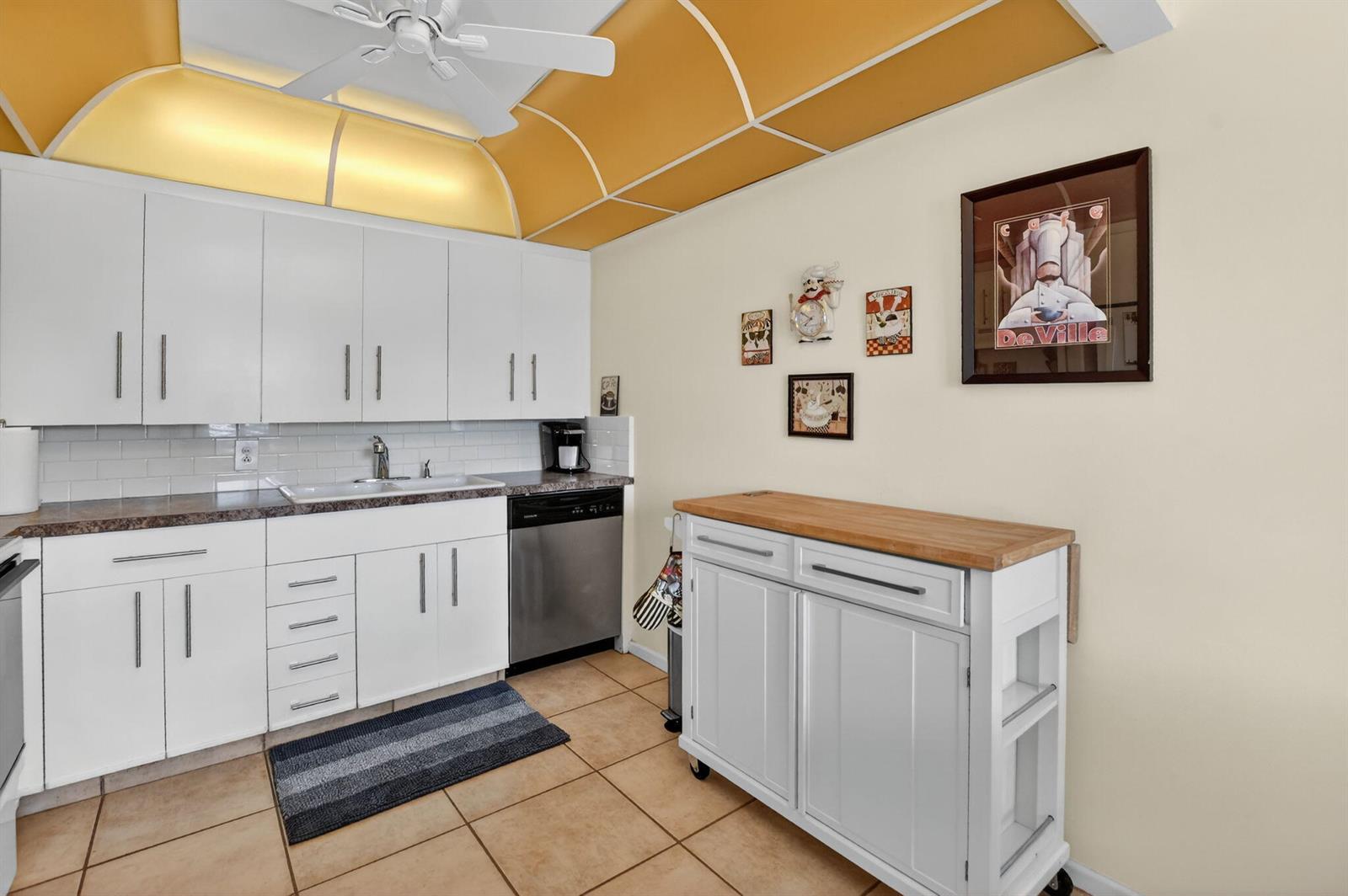 A kitchen features white cabinets, a butcher block island, and a yellow vaulted ceiling — 4008 Hythe A, Boca Raton FL 33434, BOCA RATON, FL