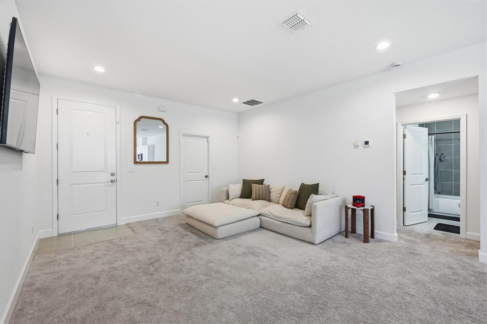 A living room features a beige sectional sofa, gray carpeting, and white walls — 8452 Dorsey Street, Spring Hill FL 34608, SPRING HILL, FL