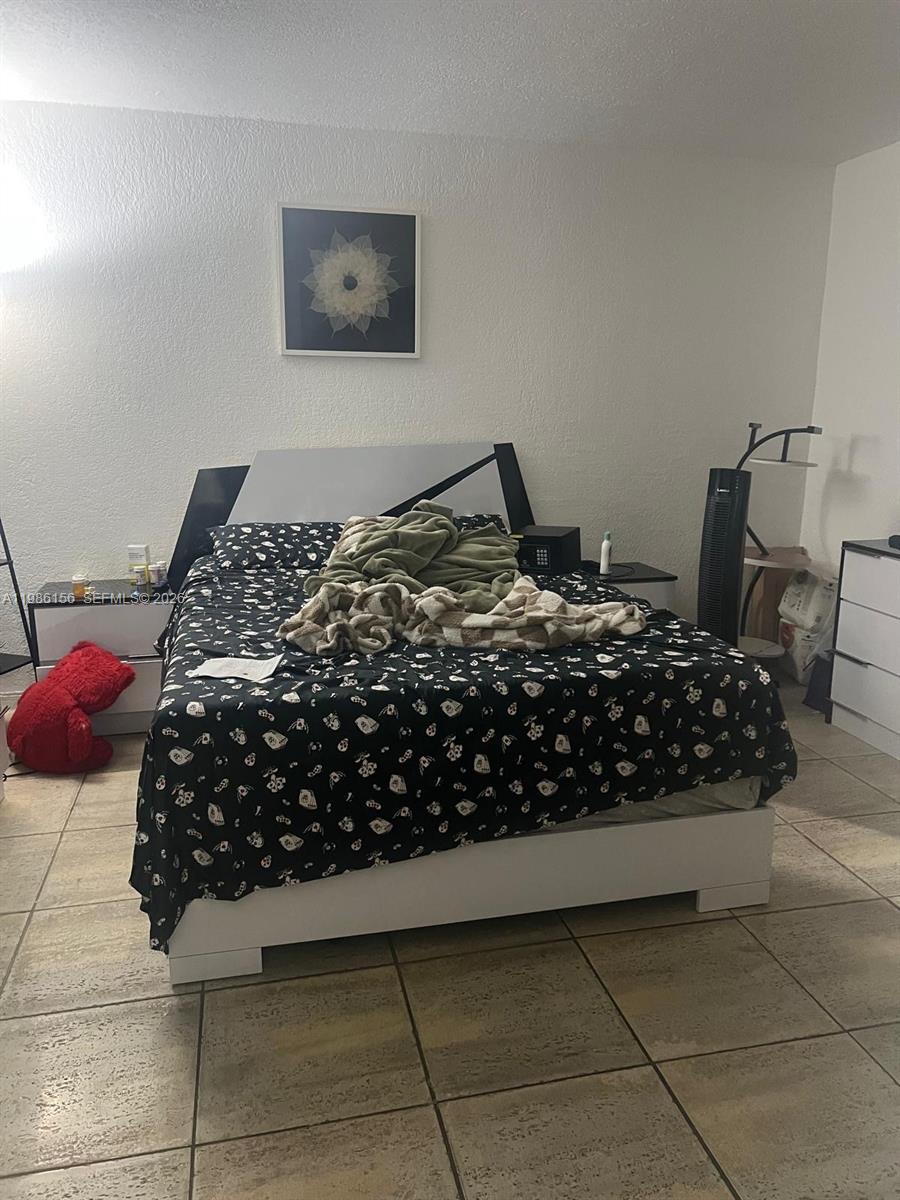 A bedroom features a bed with a patterned black comforter, white furniture, and tiled flooring — 3901 SW 112th Ave # 34, Miami FL 33165, MIAMI, FL