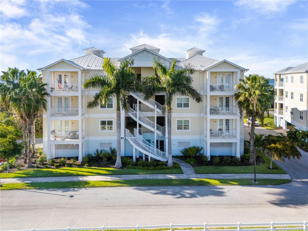 A three-story apartment building with exterior staircases, balconies, and palm trees in front — 3431 79TH STREET CIRCLE W UNIT 202, BRADENTON, FL
