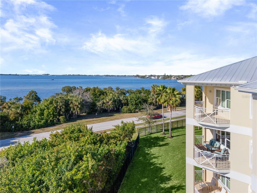 An elevated view shows a multi-story building with balconies overlooking a road, trees, and water — 3431 79TH STREET CIRCLE W UNIT 202, BRADENTON, FL