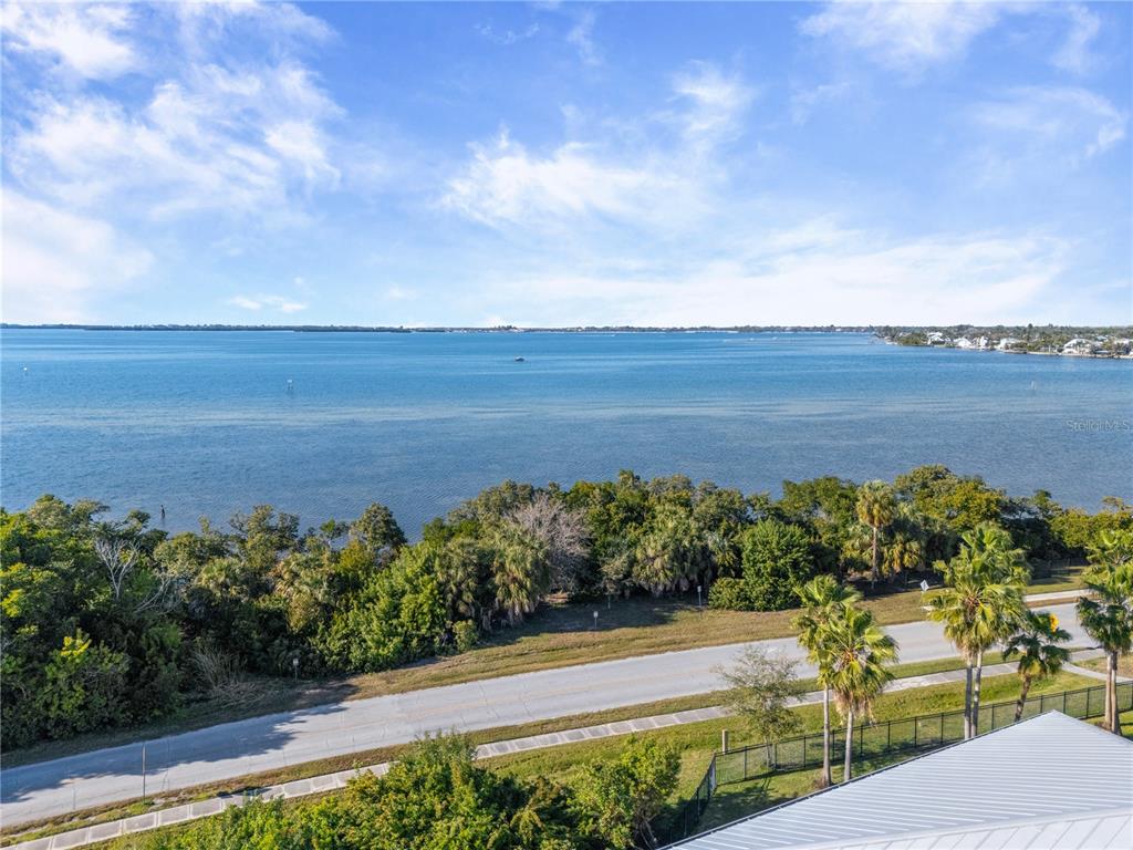 An elevated view of a coastal road, lush vegetation, and a wide expanse of water — 3431 79TH STREET CIRCLE W UNIT 202, BRADENTON, FL
