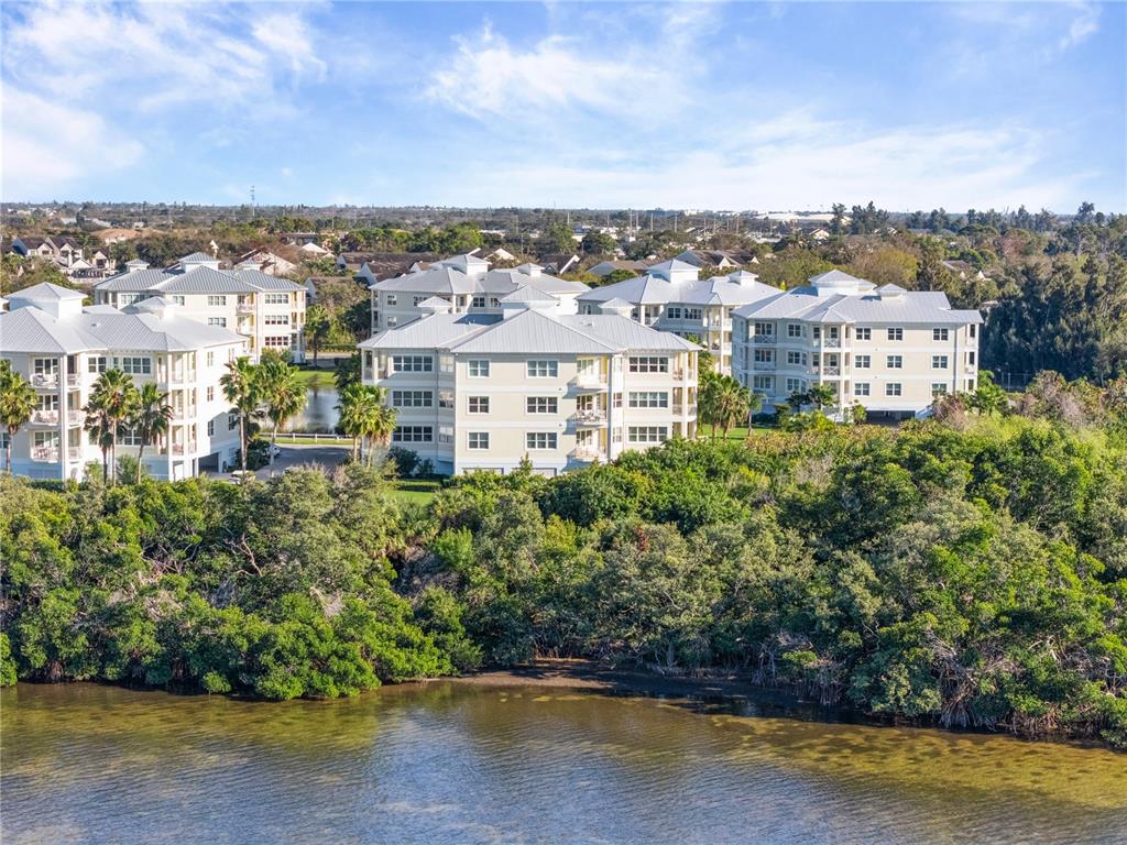 An aerial view shows several multi-story apartment buildings situated near a body of water — 3431 79TH STREET CIRCLE W UNIT 202, BRADENTON, FL