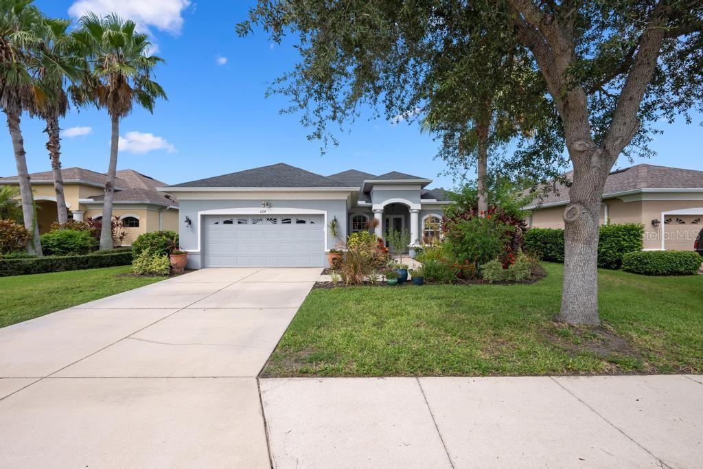 A single-story house with a gray garage, light blue siding, and a landscaped front yard — 264 DAHLIA COURT, BRADENTON, FL