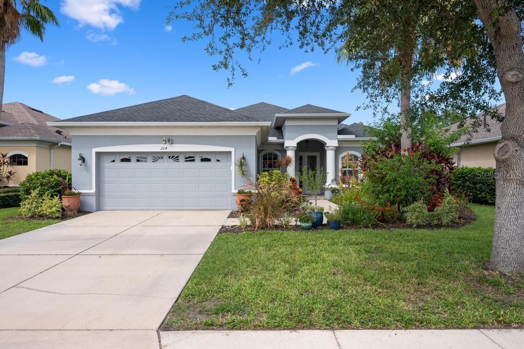 A single-story house with a gray exterior, a two-car garage, and a landscaped front yard — 264 DAHLIA COURT, BRADENTON, FL