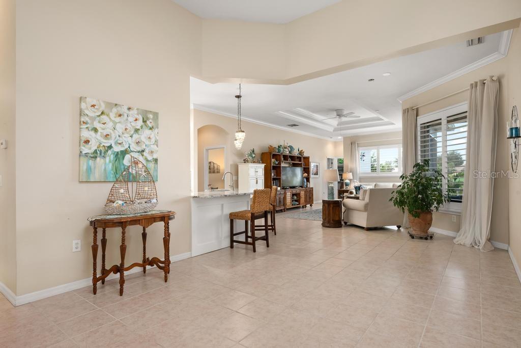An open-concept living area features tile flooring, a kitchen island with bar seating, and furniture — 264 DAHLIA COURT, BRADENTON, FL