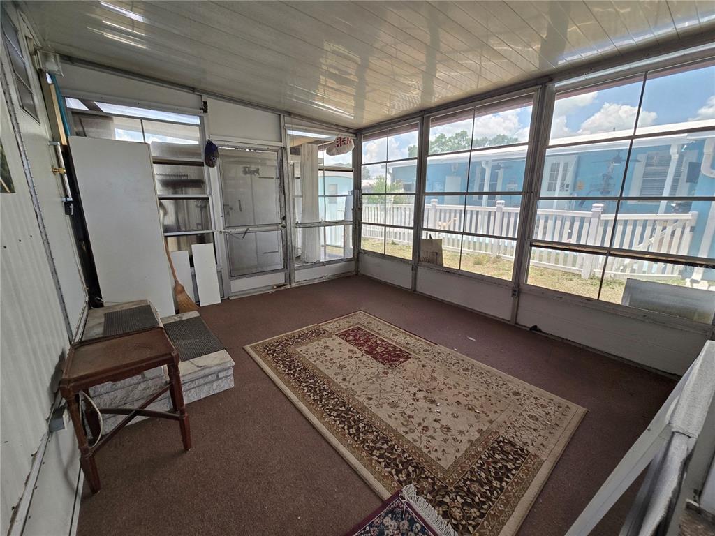 A screened-in porch with a brown carpet, a patterned area rug, and large windows — 6235 PARKSEND LANE, ZEPHYRHILLS, FL