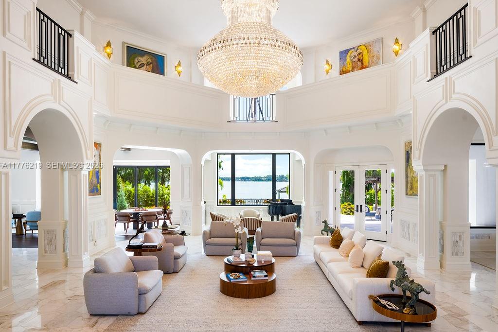 A grand, high-ceilinged living room features a large crystal chandelier, white walls, and lake views — 570 Manor Rd, Maitland, Winter Park FL 32751, WINTER PARK, FL