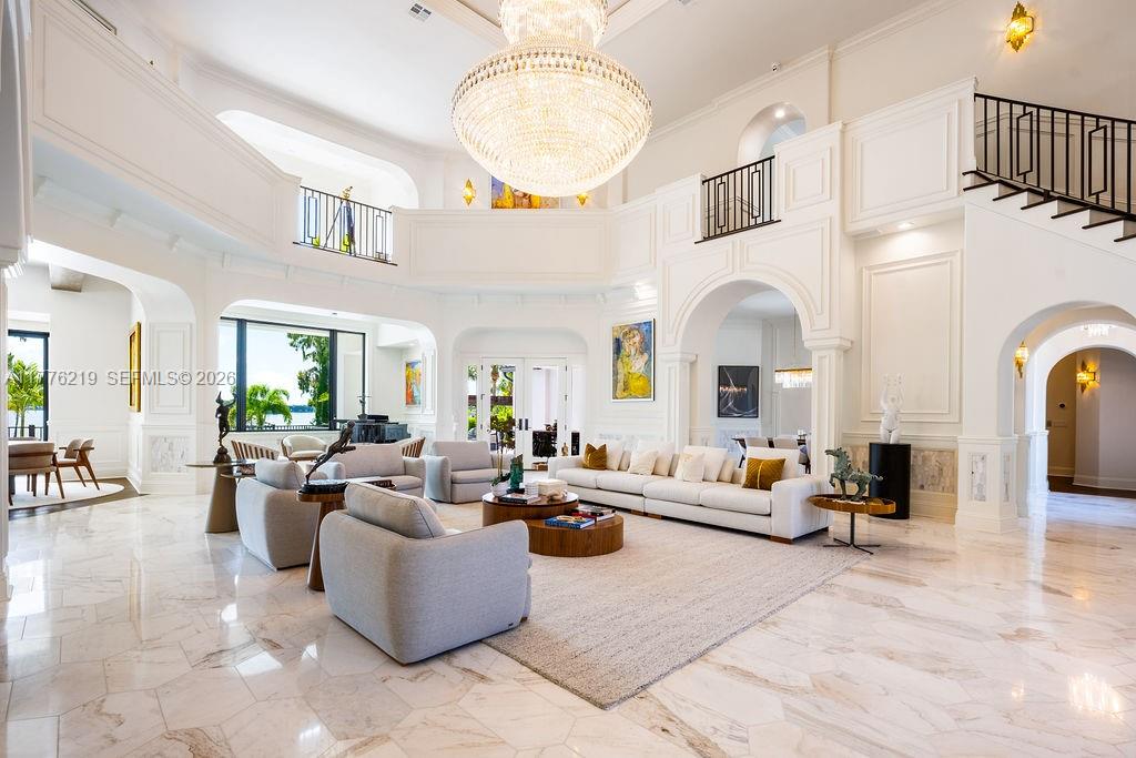 A spacious, high-ceilinged living room features white walls, marble floors, and a large crystal chandelier — 570 Manor Rd, Maitland, Winter Park FL 32751, WINTER PARK, FL