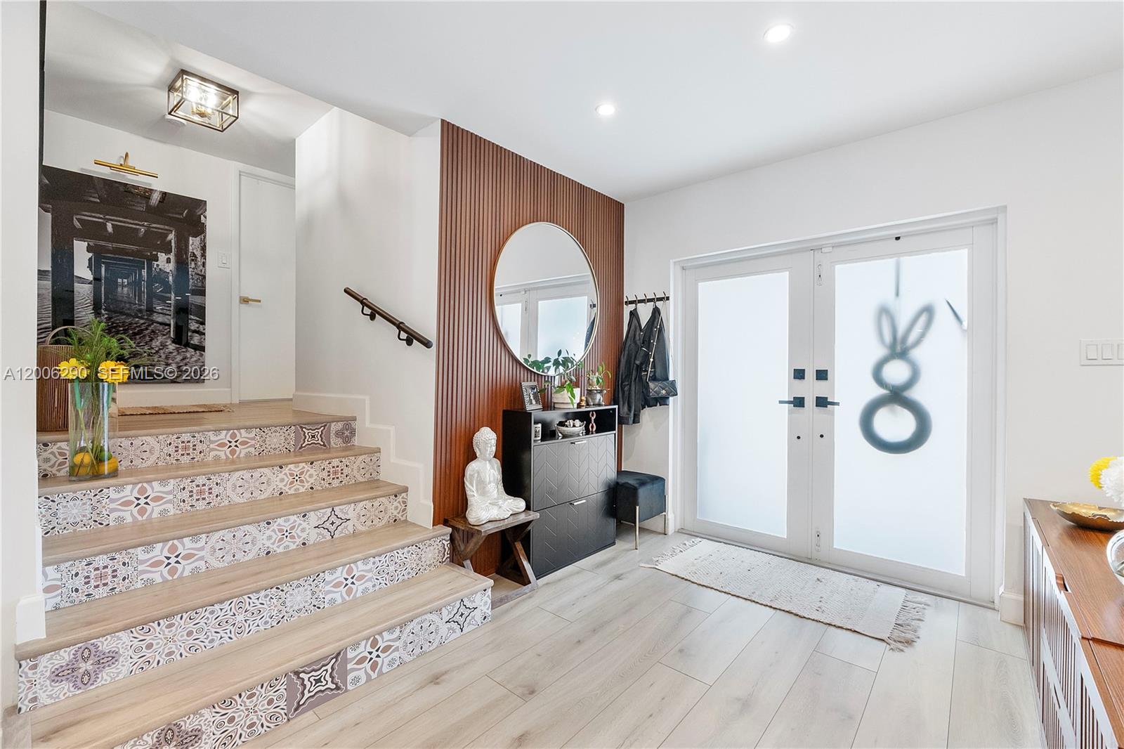 An entryway features a patterned staircase, a wood-slatted accent wall with a mirror, and double doors — 14830 N Spur Dr, Miami FL 33161, MIAMI, FL