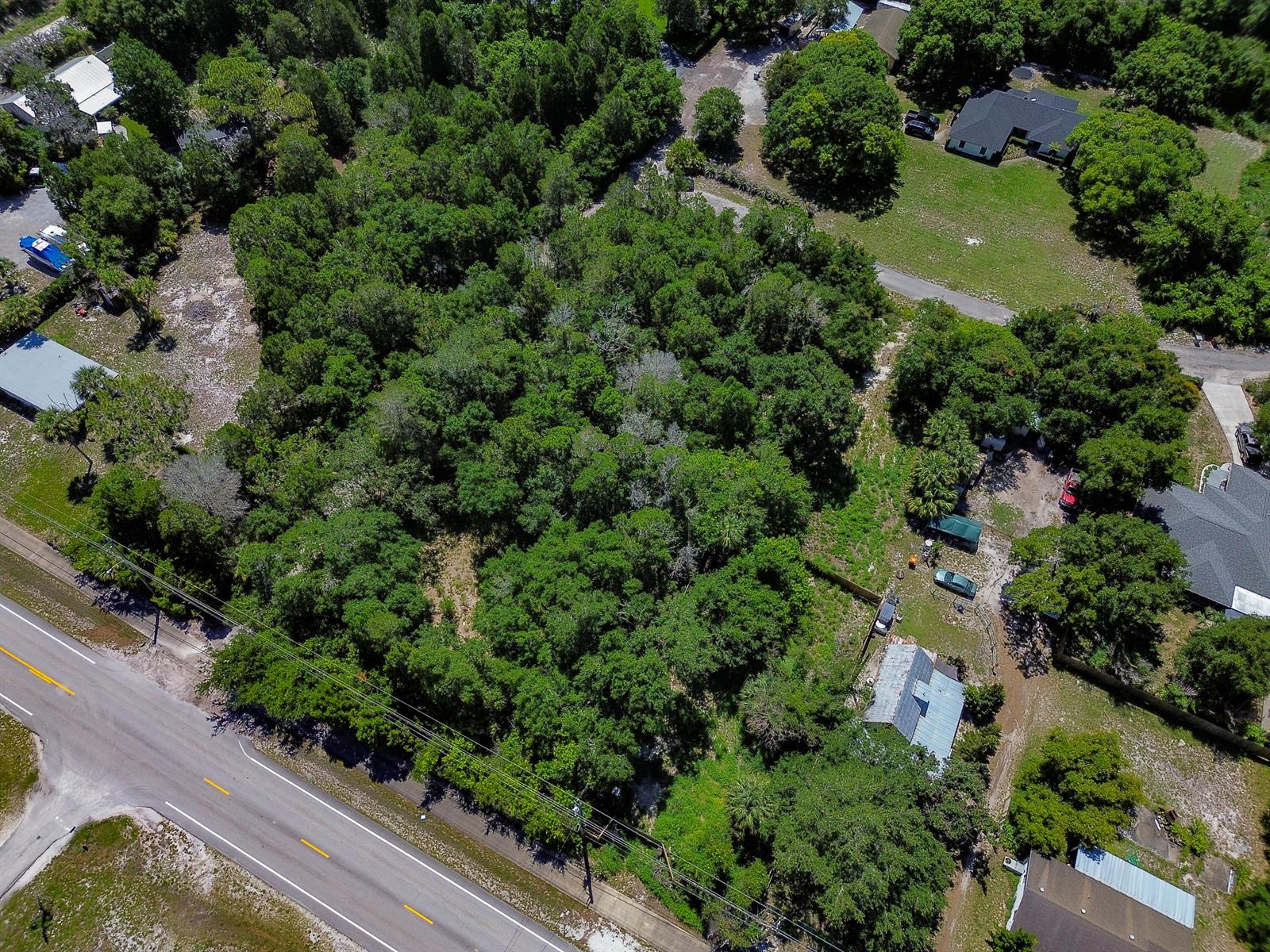 An aerial view shows a wooded lot bordered by a road and nearby residential properties — 12850 Roseland Road, Sebastian FL 32958, SEBASTIAN, FL