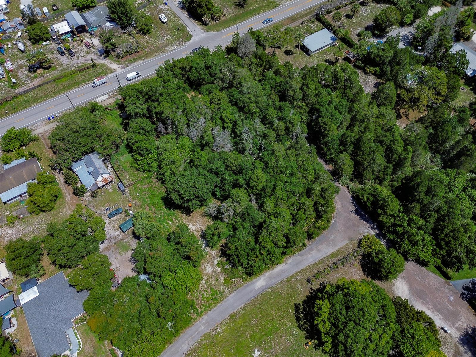 An aerial view shows a wooded lot bordered by a road and nearby houses — 12850 Roseland Road, Sebastian FL 32958, SEBASTIAN, FL