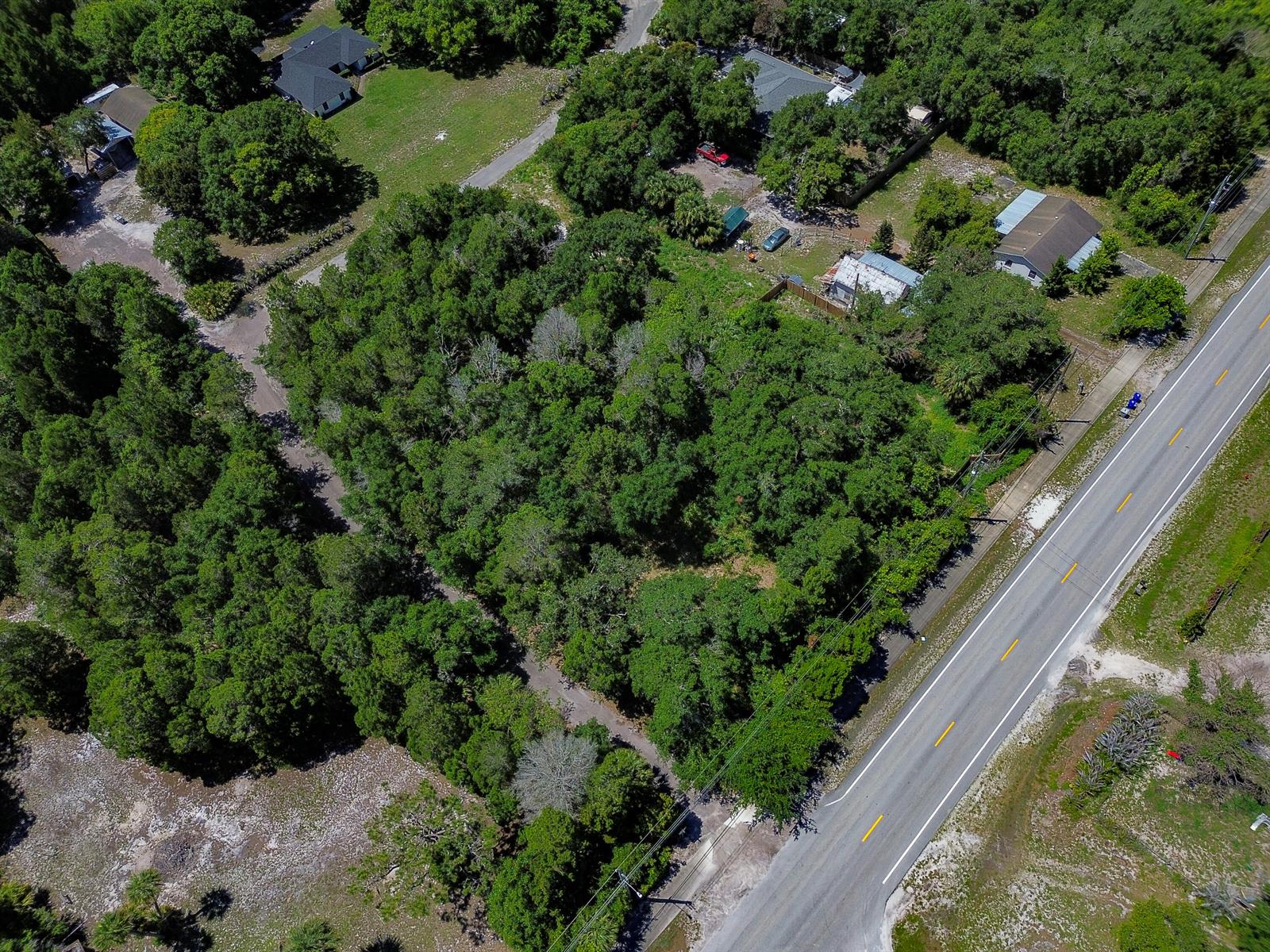 An aerial view shows a wooded lot situated between a residential road and a highway — 12850 Roseland Road, Sebastian FL 32958, SEBASTIAN, FL