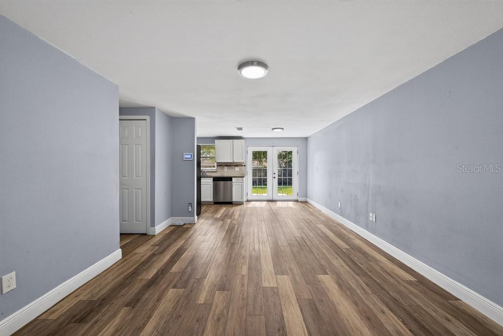 An open-concept living area features light blue walls, wood-look flooring, and a small kitchen — 3417 DANNY BRYAN BOULEVARD, TAMPA, FL