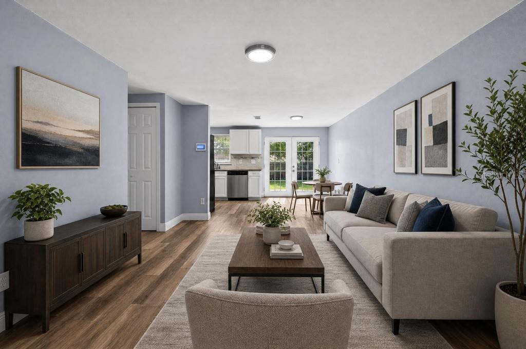 A living room with light blue walls, wood-look flooring, a beige sofa, and an open kitchen — 3417 DANNY BRYAN BOULEVARD, TAMPA, FL
