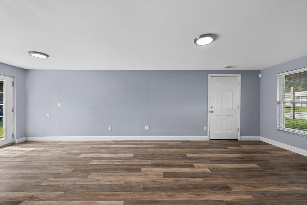 An empty room with light blue walls, wood-look flooring, two ceiling lights, and two doors — 3417 DANNY BRYAN BOULEVARD, TAMPA, FL