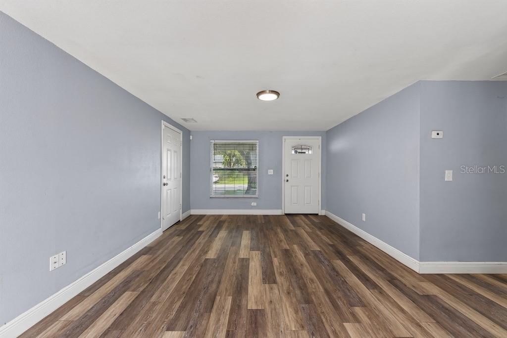 An empty room features light blue walls, wood-look flooring, a window, and two white doors — 3417 DANNY BRYAN BOULEVARD, TAMPA, FL