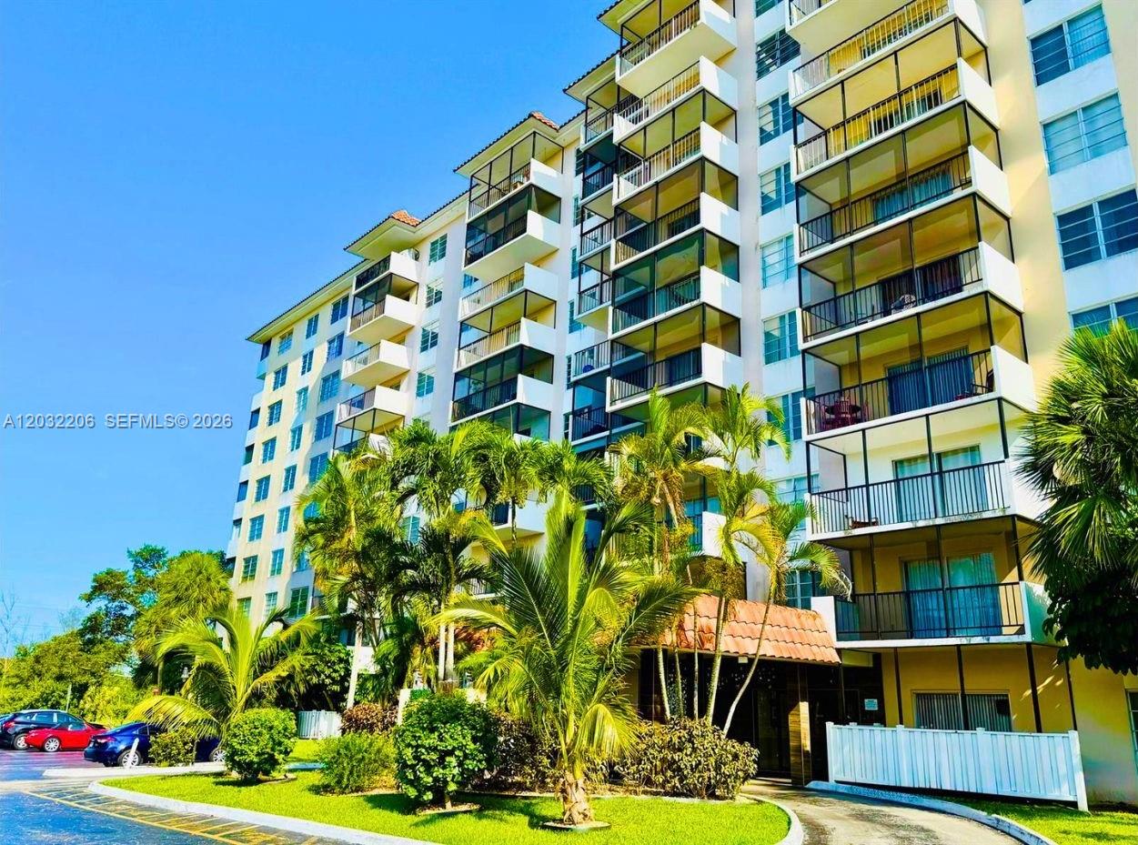 A multi-story residential building features stacked balconies with screened enclosures and surrounding palm trees — 4164 Inverrary Dr # 204, Lauderhill FL 33319, LAUDERHILL, FL