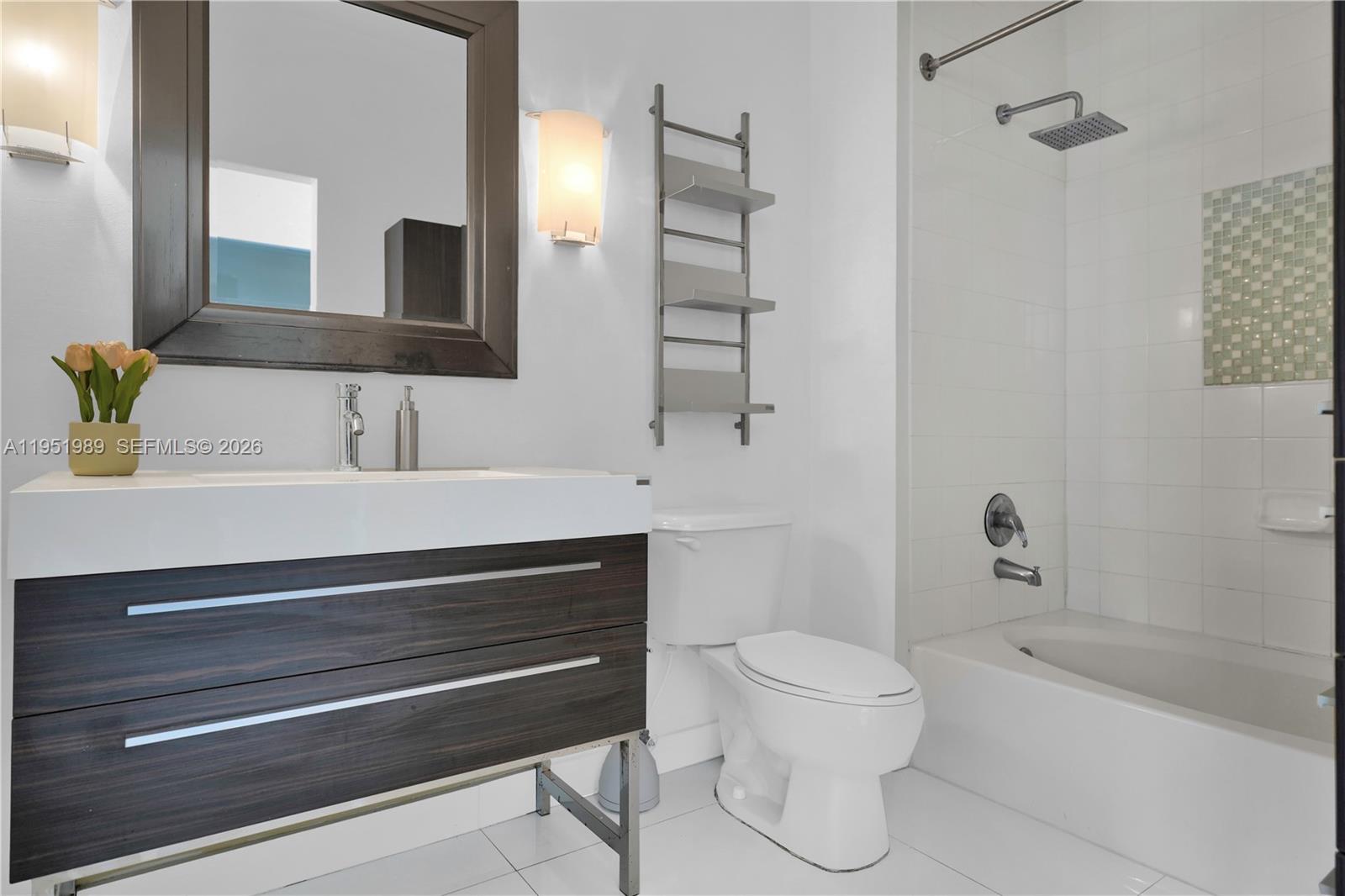 A modern bathroom features a dark wood vanity, white toilet, and a tiled shower-tub combo — 2001 Biscayne Blvd # 3213, Miami FL 33137, MIAMI, FL