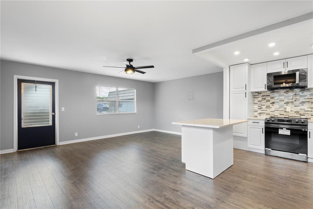 A kitchen and living area feature gray walls, dark wood flooring, and white cabinetry — 201 BEDFORD STREET UNIT 79, SUN CITY CENTER, FL
