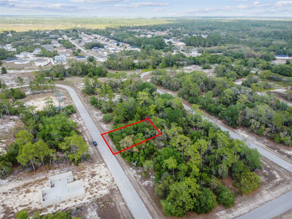 An aerial view shows a rectangular plot of land outlined in red near a road — 1305 HOMOSASSA COURT, KISSIMMEE, FL