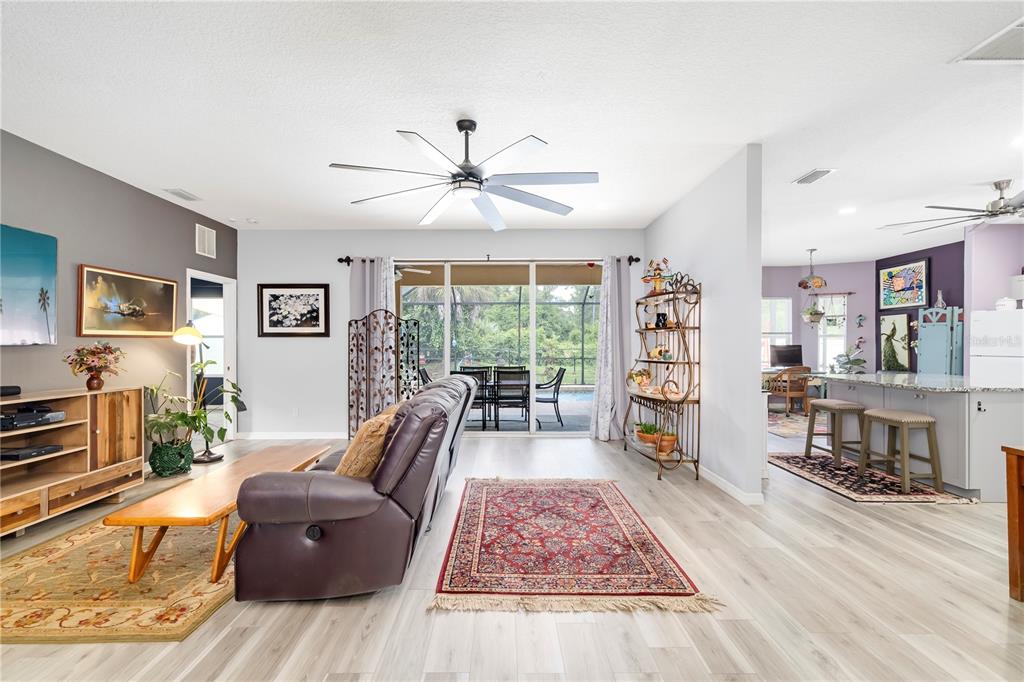 A living room with light wood floors, a ceiling fan, and a view of a pool — 2434 BISMARCK ROAD, NORTH PORT, FL