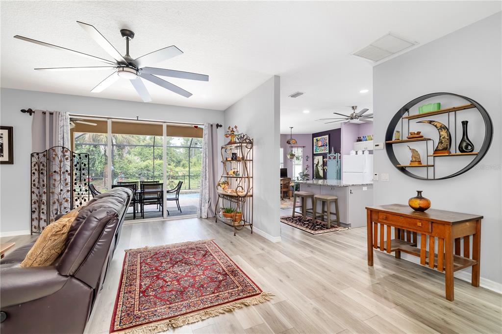 A living room with light wood flooring, a ceiling fan, and a view of a pool — 2434 BISMARCK ROAD, NORTH PORT, FL