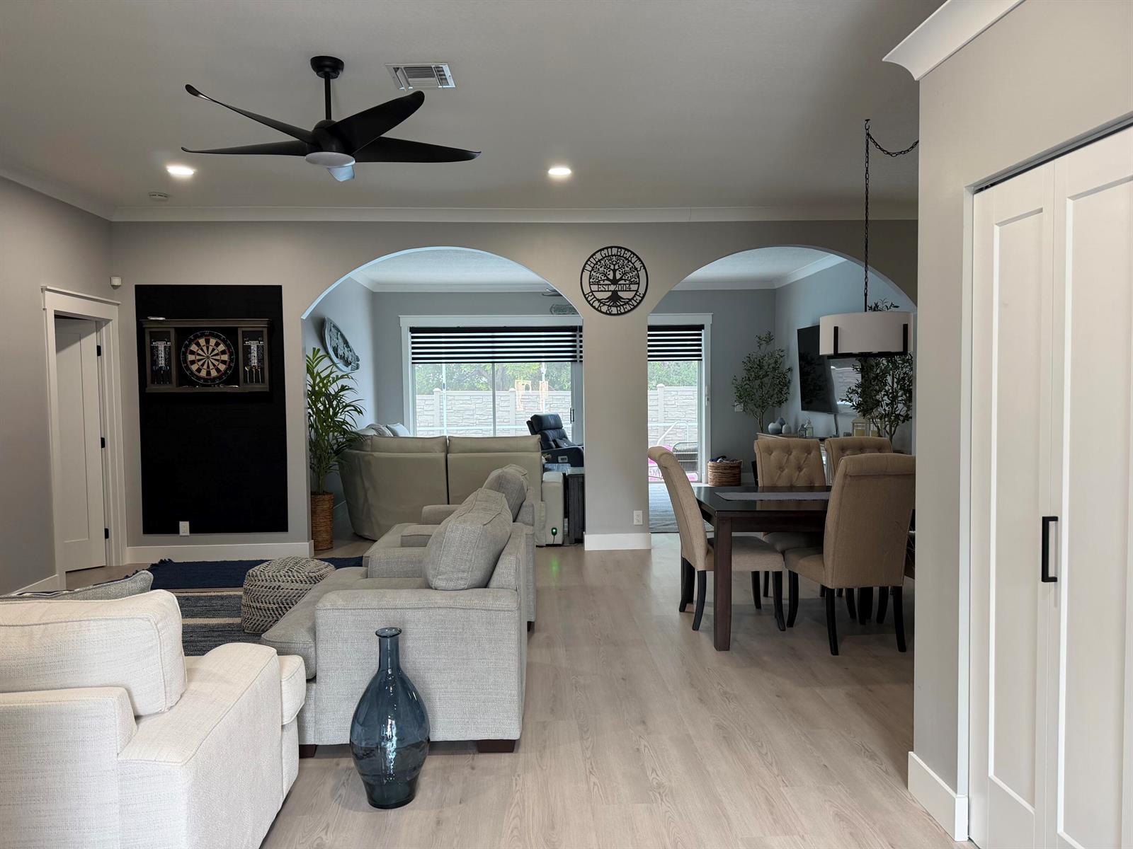 An open-concept living and dining area features arched transitions, light wood flooring, and neutral furniture — 3755 Spring Crest Court, Lake Worth FL 33467, LAKE WORTH, FL