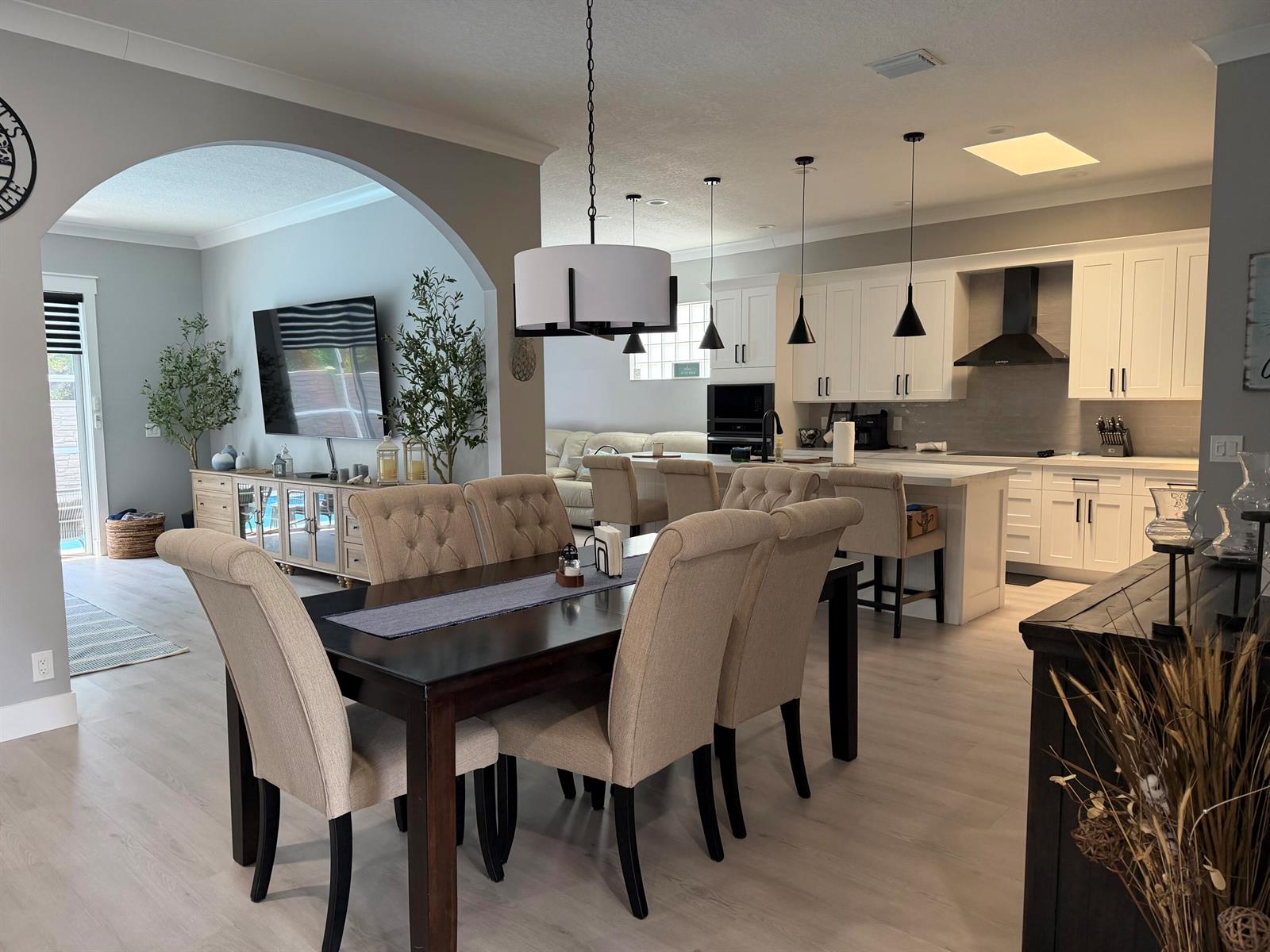 An open-concept dining room and kitchen featuring light wood floors, white cabinetry, and neutral furniture — 3755 Spring Crest Court, Lake Worth FL 33467, LAKE WORTH, FL