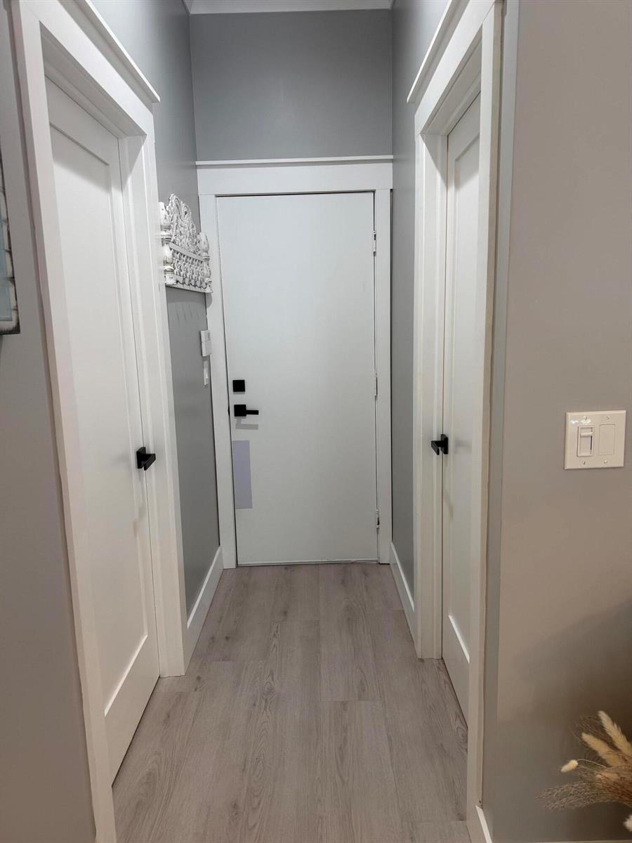 A hallway features light wood-look flooring, gray walls, and three white doors with black hardware — 3755 Spring Crest Court, Lake Worth FL 33467, LAKE WORTH, FL